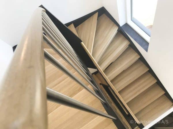 Sort halvsvingstrappe fra Vejletrappen med trappetrin i eg og trappe gelænder i sort og stål.