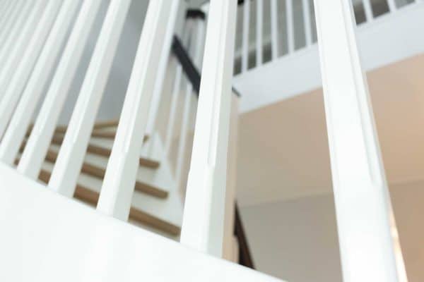 Trætrappe udformet som en halvsvingstrappe med hvide trappe vange, sort trappegelænder og trappetrin i eg fra Vejletrappen