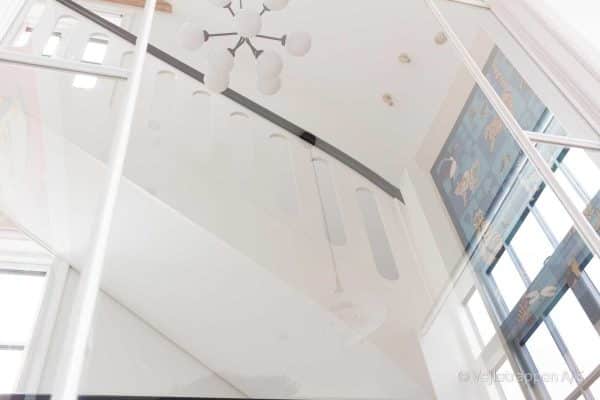Hvid trætrappe designet som en halvsvingstrappe med pladegelænder og sort gelænder fra Vejletrappen