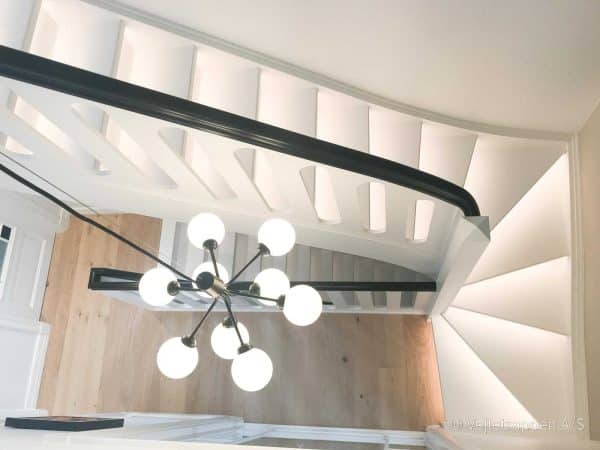 Hvid trætrappe designet som en halvsvingstrappe med pladegelænder og sort gelænder fra Vejletrappen