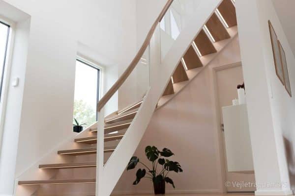 Hvid trætrappe udformet som en kvartsvingstrappe / krumningstrappe med trappetrin i eg og glasværn samt trappebelysning under trin fra Vejletrappen
